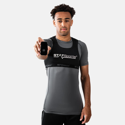 Man wearing a gray and black sports outfit with 'STATSports' branding, holding a device.